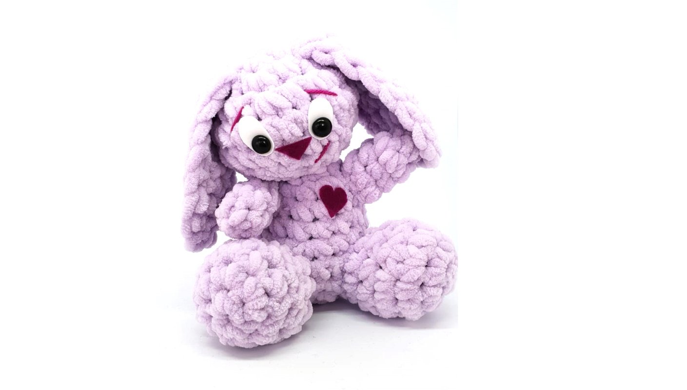 Fliederfarbener gehäkelter Amigurumi-Hase mit Schlappohren und Herzapplikation