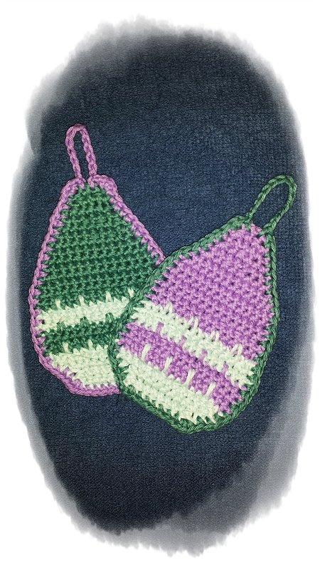 Zwei gehäkelte eiförmige Anhänger in Grün, Weiß und Lila mit Schlaufen