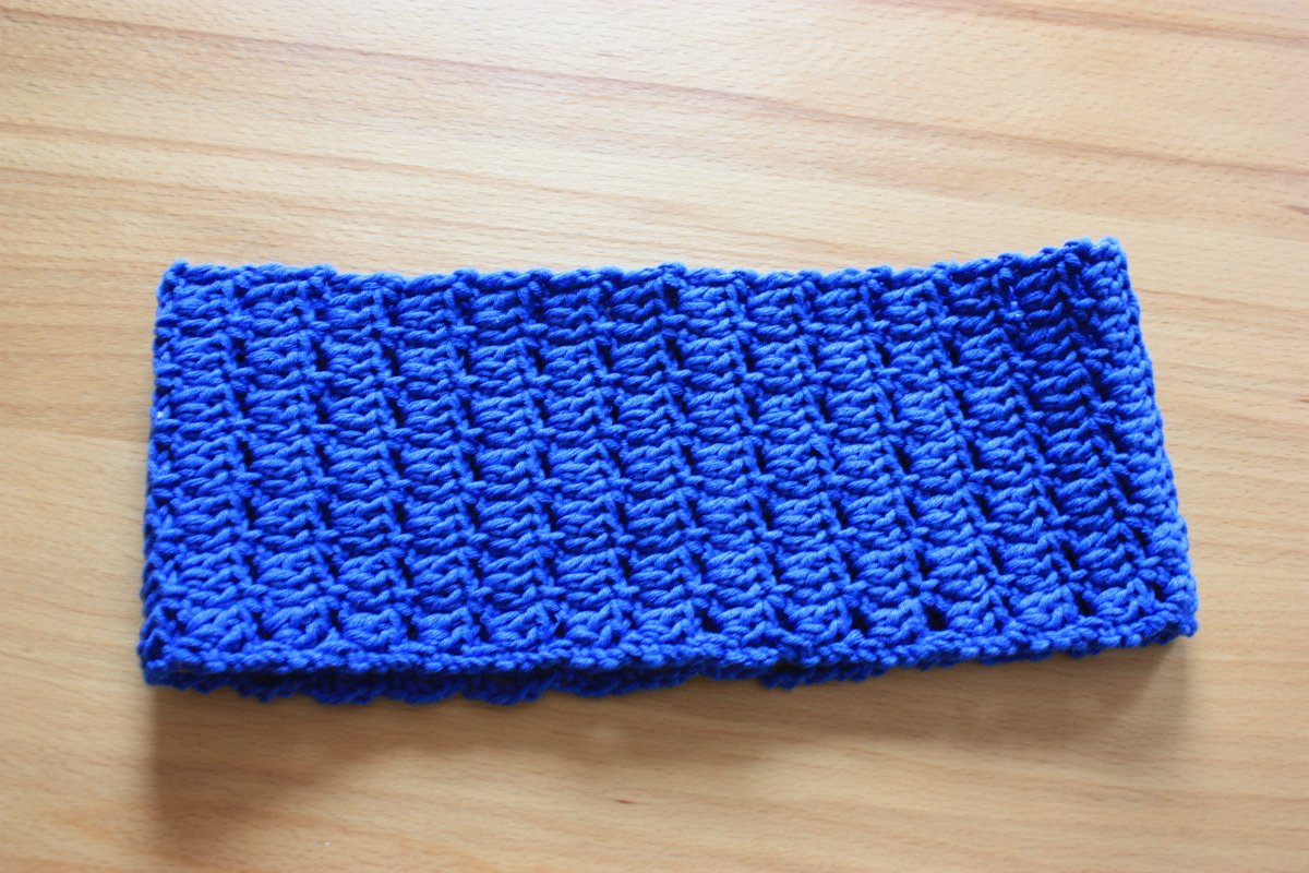 Gehäkeltes blaues Stirnband auf hellem Holzuntergrund