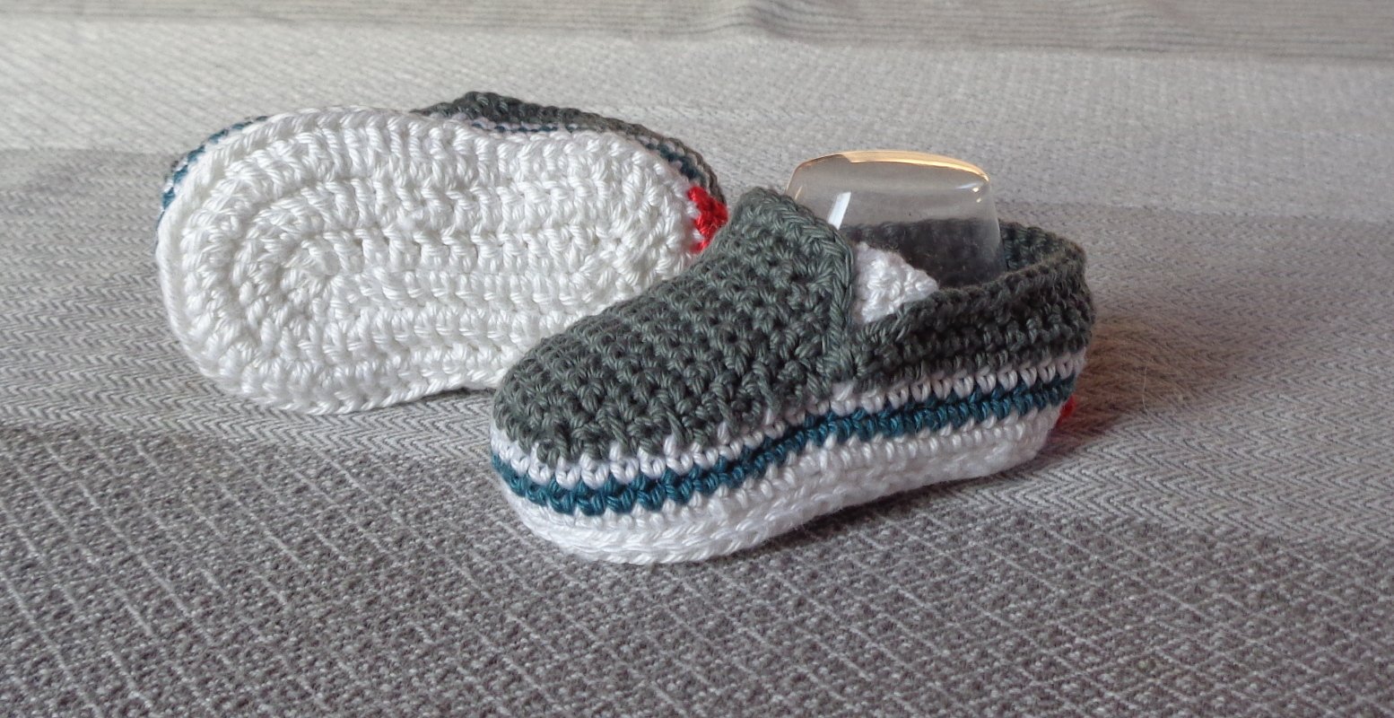 Gehäkeltes Paar Babyschuhe grau weiß mit petrolfarbener Zierlinie