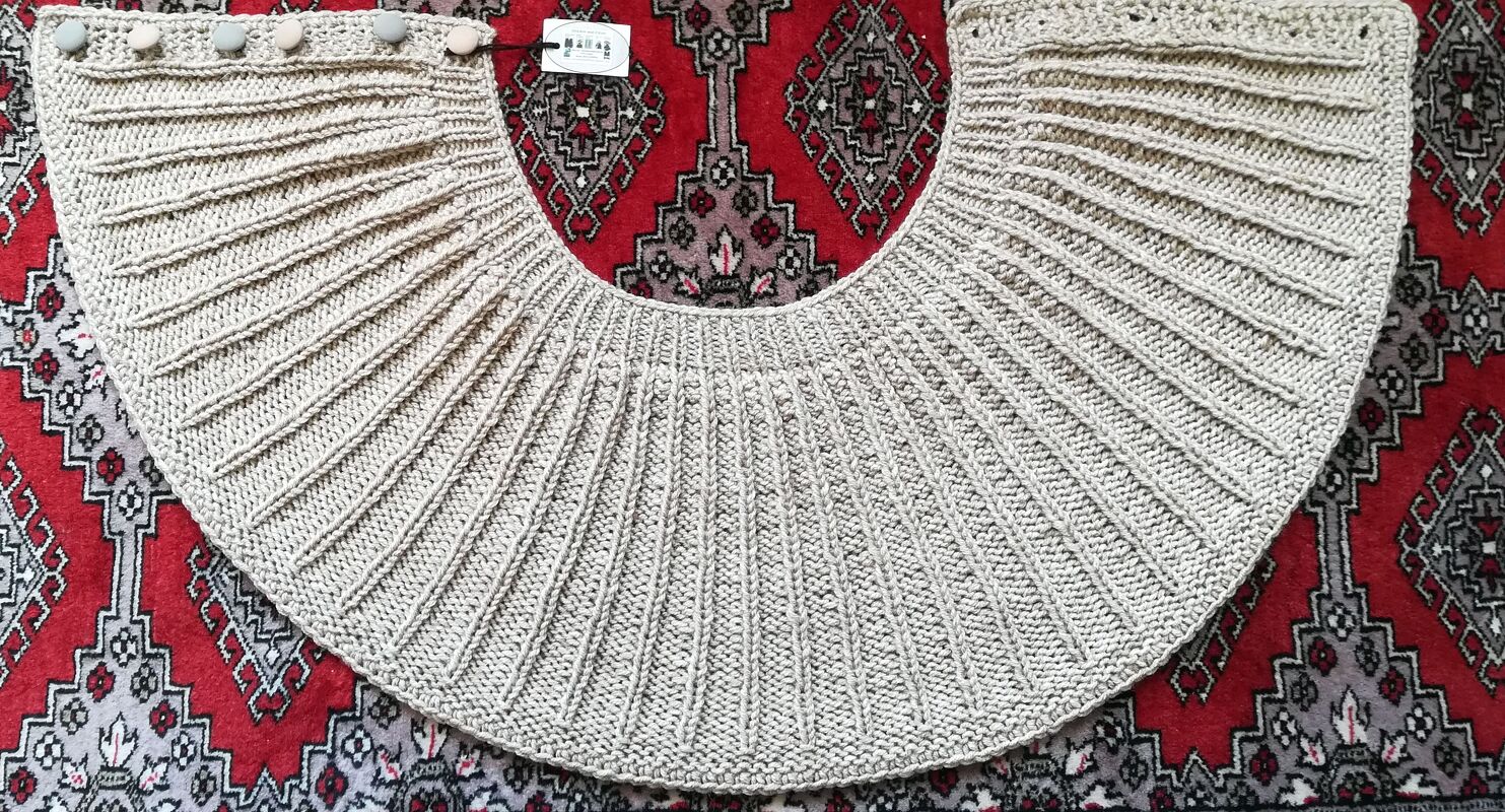 Beige gestrickte Rundpasse mit schmalen vertikalen Rippen und Knöpfen an der Kante