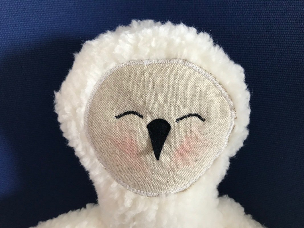 Nahaufnahme eines weißen Plüsch-Eulen-Kuscheltieres mit Leinen-Gesicht, gestickten Augen und schwarzem Schnabel