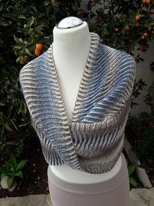Knitted ribbed infinity cowl in blue, gray and beige draped on a white mannequin