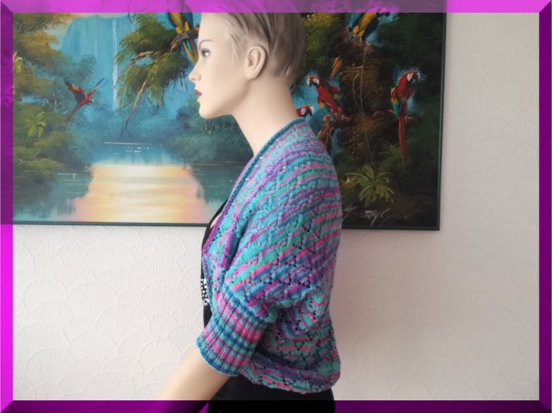 Schaufensterpuppe mit kurzärmeligem, offen geschnittenem Seelenwärmer aus Strick in Türkis, Pink und Lila.