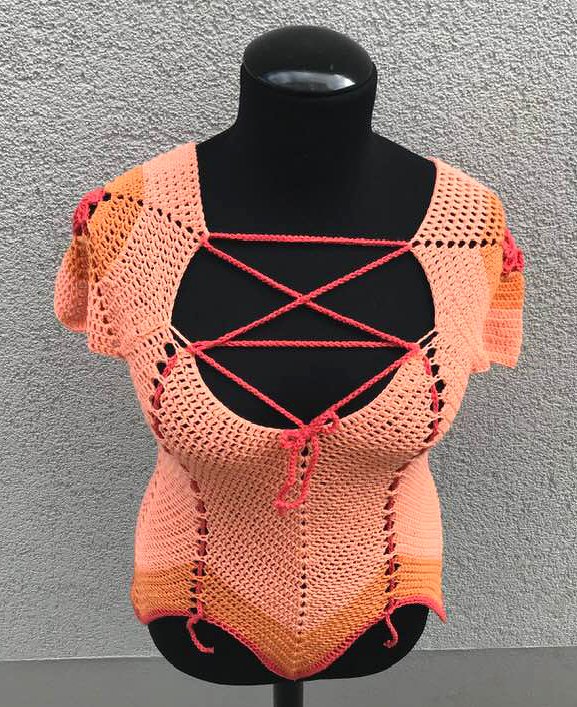 Gehäkeltes Damen-Top in Pfirsich-Orange mit Kreuzschnürung auf schwarzer Schaufensterpuppe