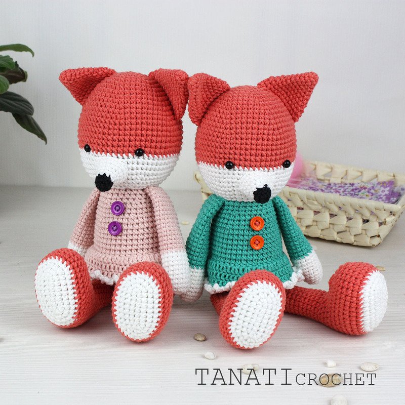 Zwei gehäkelte Fuchs-Amigurumi in rosa und türkis sitzend