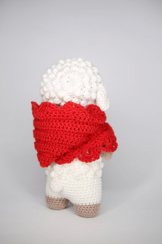Rückansicht eines gehäkelten Lamm-Amigurumi mit rotem Umhang