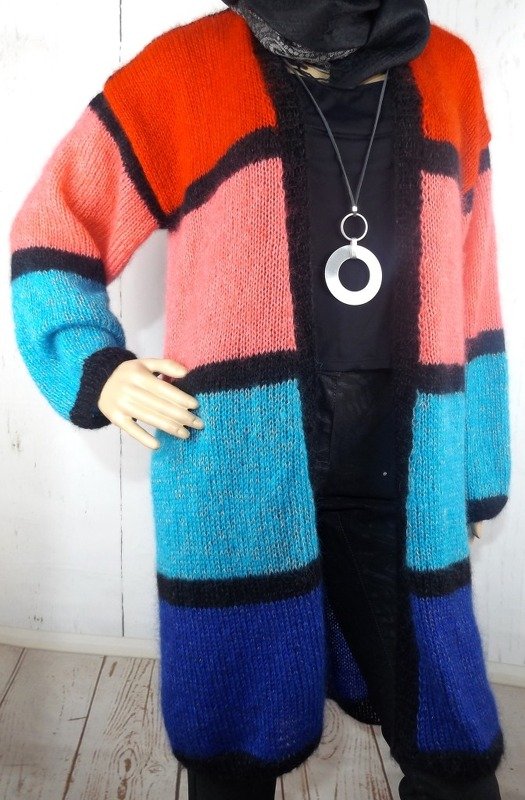 Mannequin trägt offenen, lang gestrickten Damencardigan mit orange-, rosa-, türkis- und blaufarbenen Feldern und schwarzen Linien