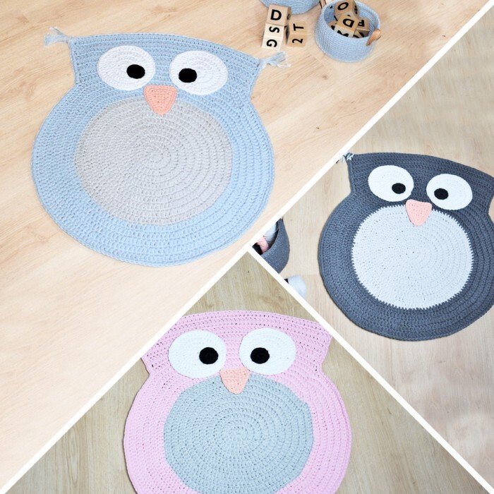 Drei gehäkelte Eulen-Teppiche in Blau, Grau und Rosa auf hellem Holzboden mit Holzspielwürfeln im Hintergrund.