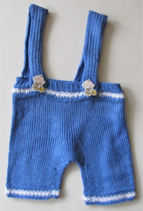 Blau gestrickte Baby-Latzhose mit breiten Trägern, weißen Streifen und Bärchenknöpfen