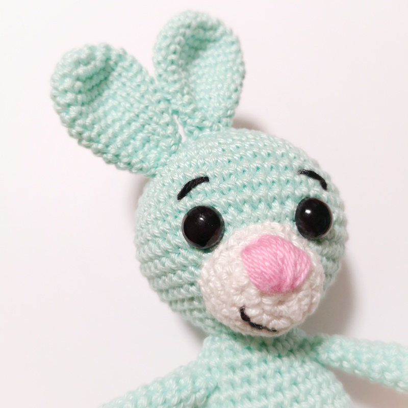 Gehäkelter mintgrüner Amigurumi-Hase mit rosa Nase und schwarzen Sicherheitsaugen