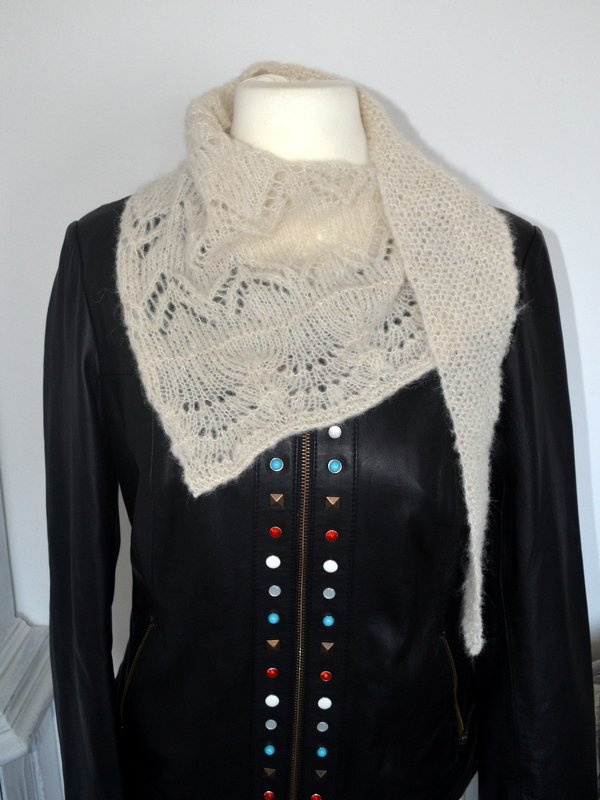 Cremefarbenes, gestricktes Dreieckstuch mit Ajourmuster auf schwarzer Lederjacke an Schaufensterpuppe