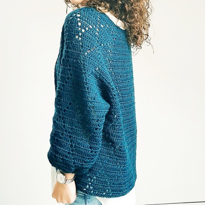 Woman wearing a teal openwork crochet cardigan with long sleeves, back and side view