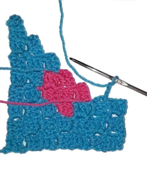 Metal crochet hook joining a pink pixel square to a teal-blue crochet corner
