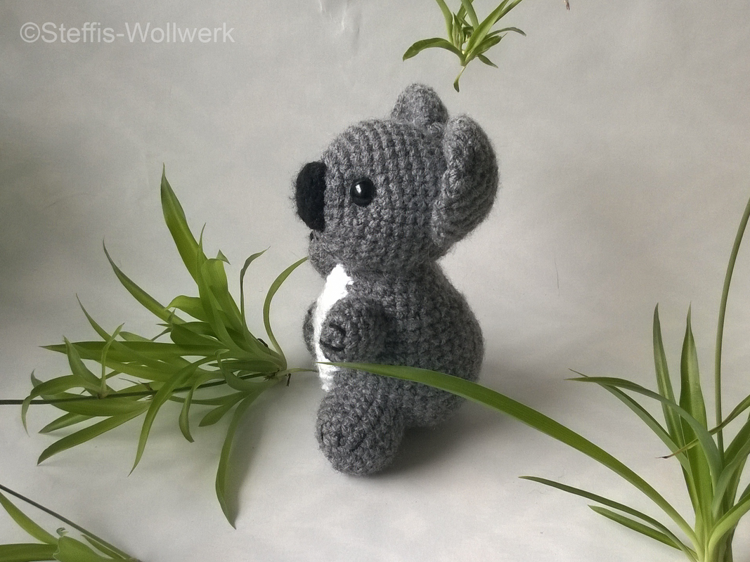 Gehäkelter grauer Amigurumi-Koala, sitzende Seitenansicht mit weißer Brust