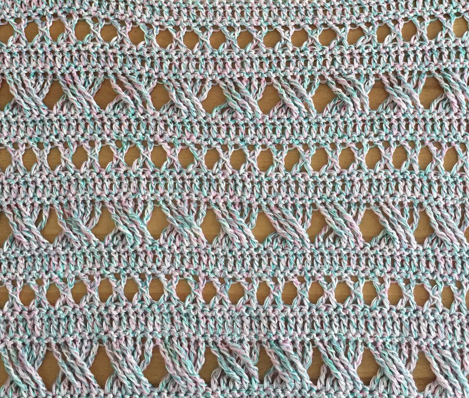 Detail einer Häkelprobe mit überkreuzten Zöpfen und Ajourreihen in pastellfarbenem Garn