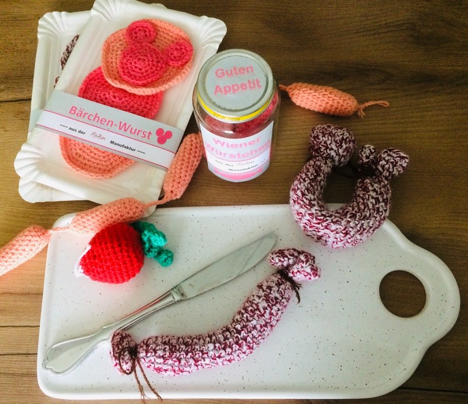 Gehäkeltes Spielküchen-Set mit Würstchen, Wurstkette, Einmachglas und Gemüse auf einem Schneidebrett
