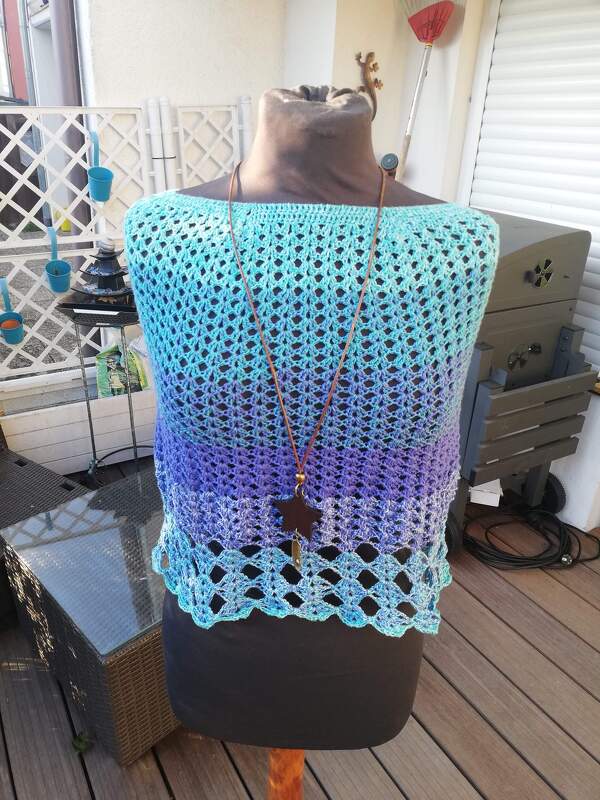 Gehäkelter Kurzponcho in Türkis und Lila mit Lochmuster auf Schneiderpuppe
