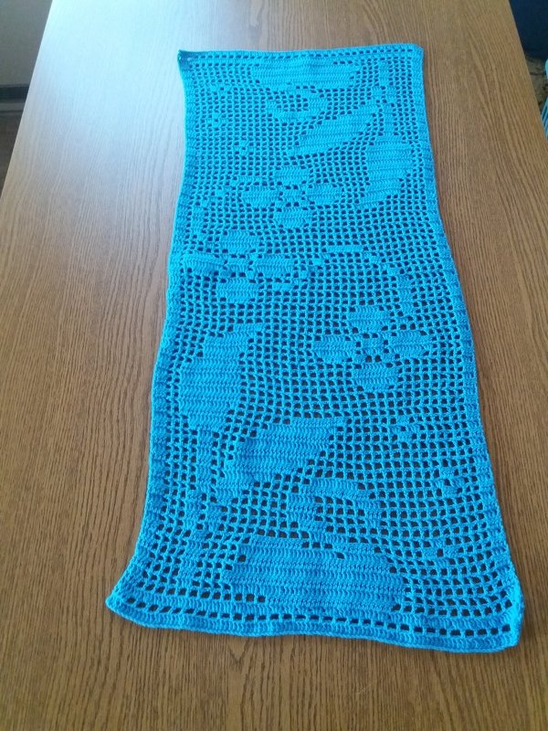 Gehäkelter türkisblauer Tischläufer mit Delfinmotiv auf Holztisch