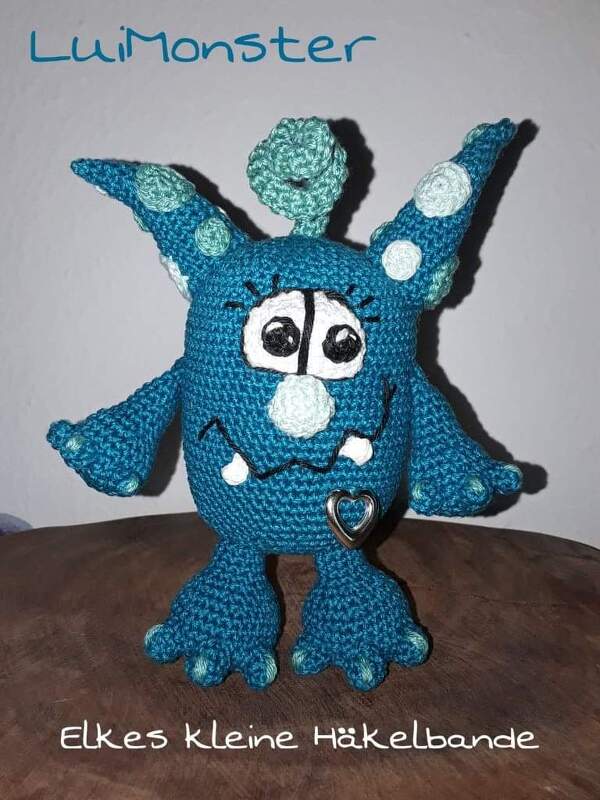 Gehäkeltes blaues Monster-Amigurumi mit Hörnern und Herzanhänger