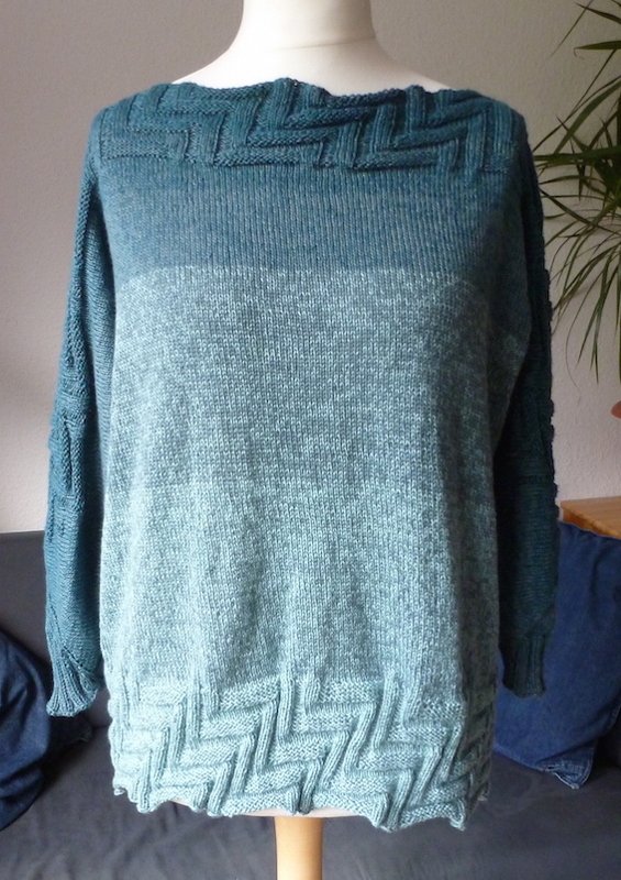 Mannequin trägt petrol-mintfarbigen Strickpullover mit Zopfdetails an Saum und Ausschnitt