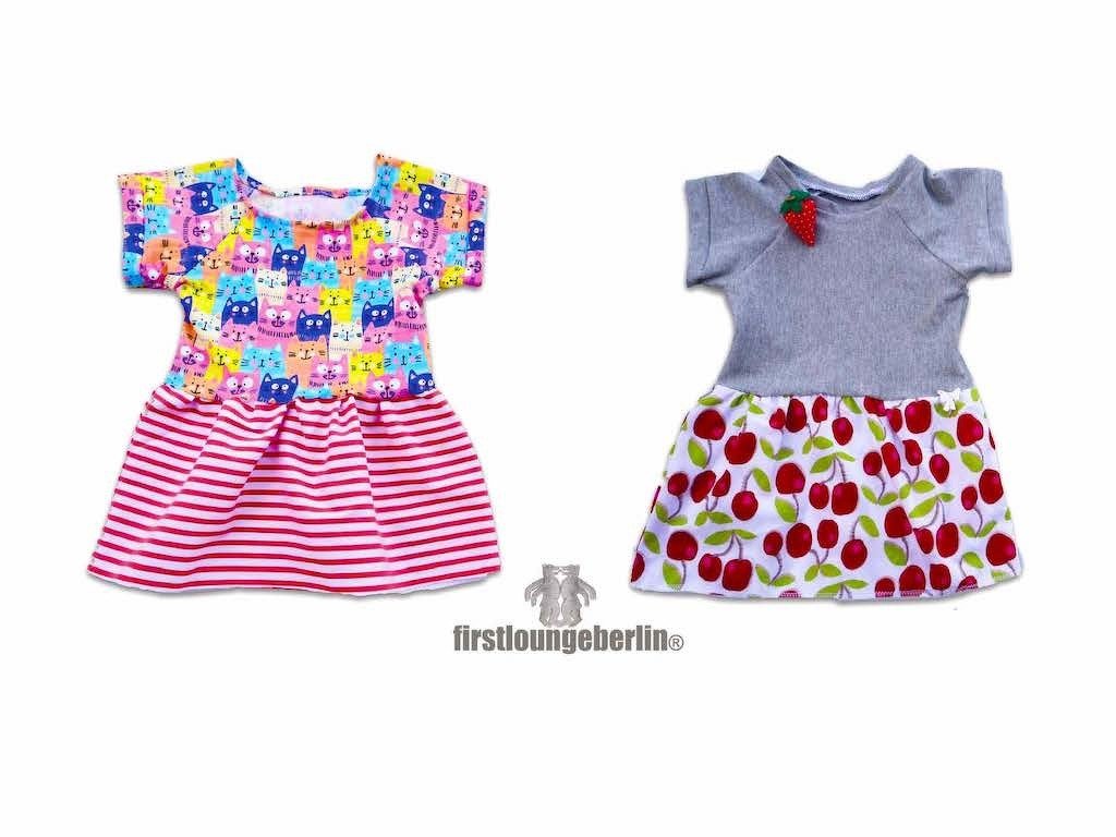 Zwei kurzärmelige Babykleider: buntes Katzenoberteil mit gestreiftem Rock; graues Oberteil mit Kirschrock und Erdbeer-Applikation.