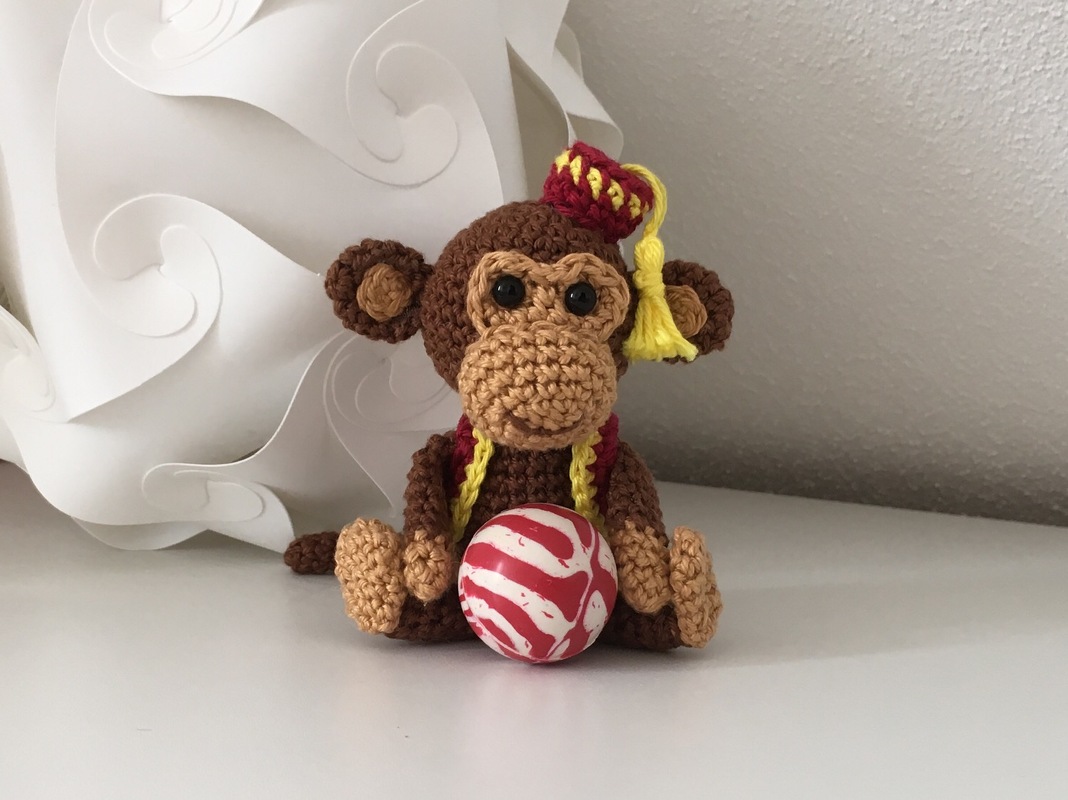 Gehäkelter Amigurumi-Affe mit rotem Fez und rot-weißem Ball