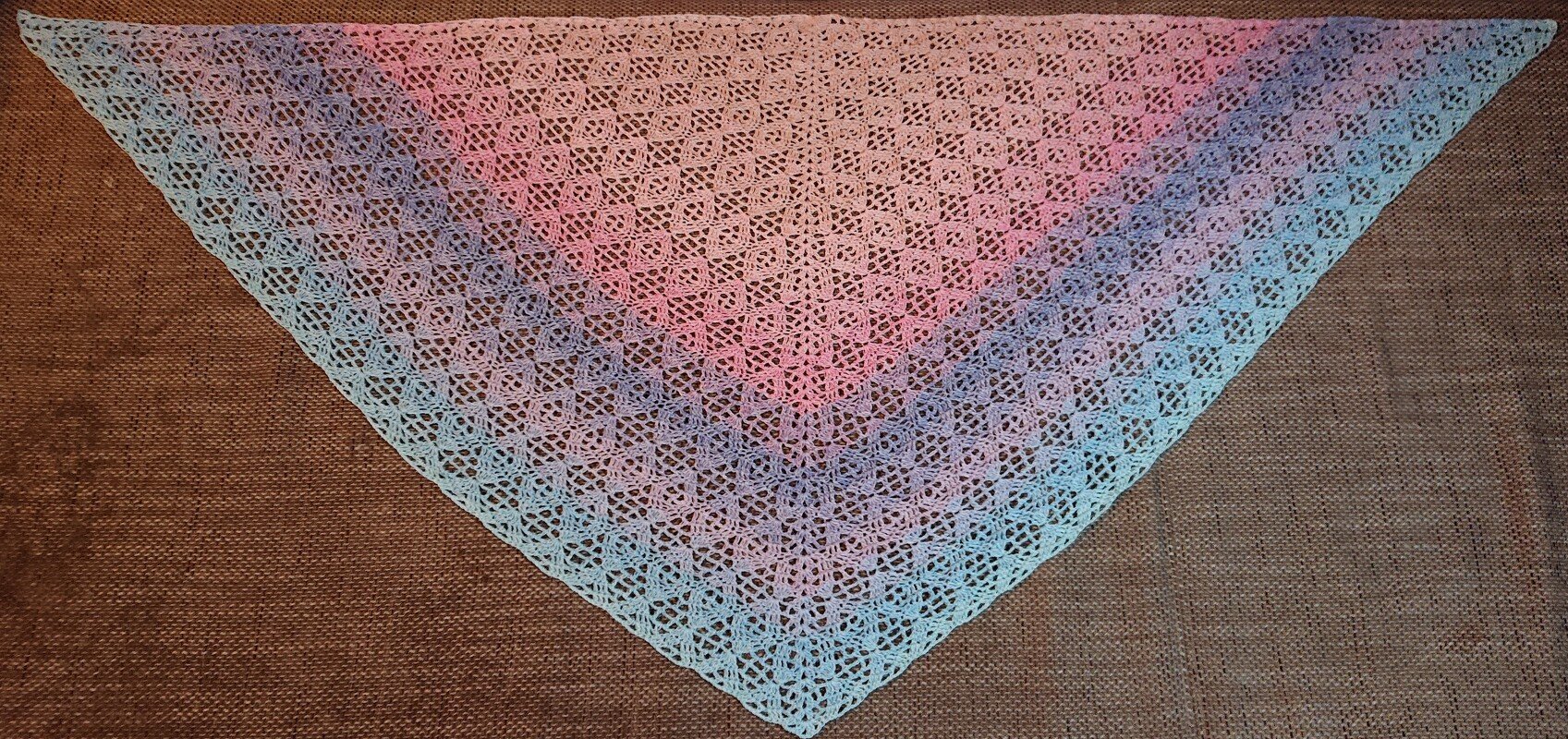 Gehäkeltes dreieckiges Tuch mit filigranem Lochmuster und Pastell-Farbverlauf von Rosa zu Blau