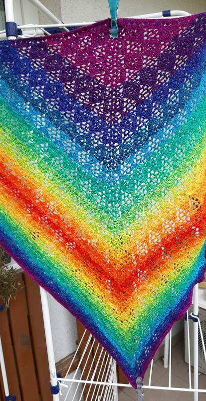 Gehäkeltes Dreieckstuch mit Regenbogenverlauf und Lochmuster an einem Wäschegestell
