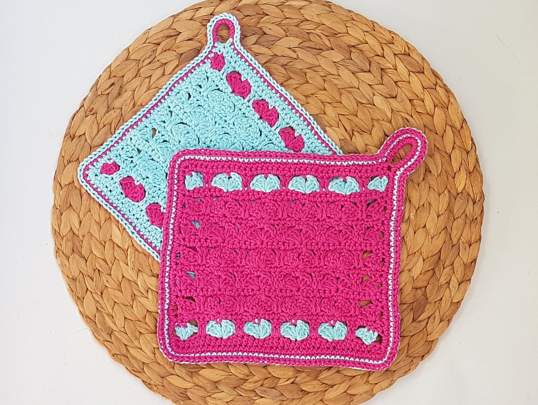 Zwei handgehäkelte Topflappen in Rosa und Hellblau mit Herzchenbordüre und Aufhängeöse
