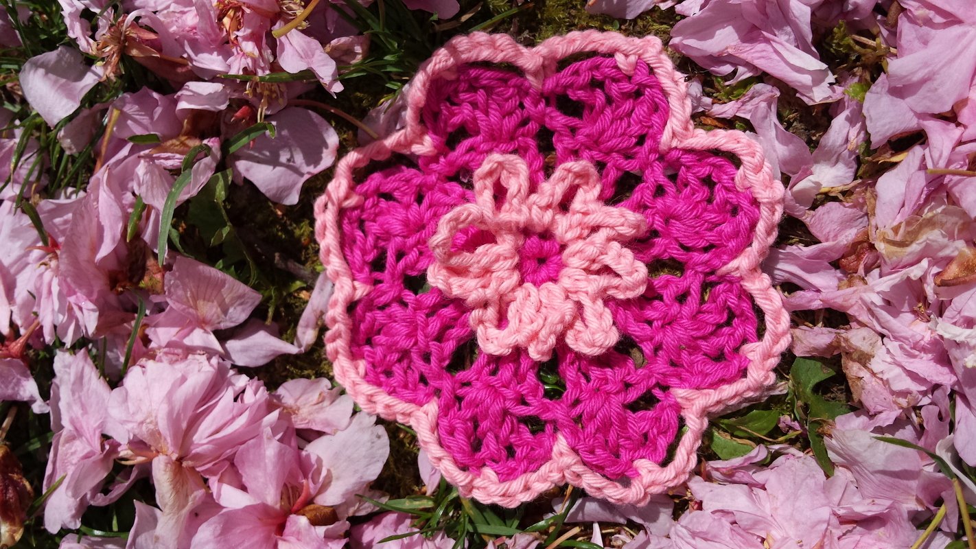 Zweifarbige gehäkelte Blume in Pink auf rosa Blütenblättern