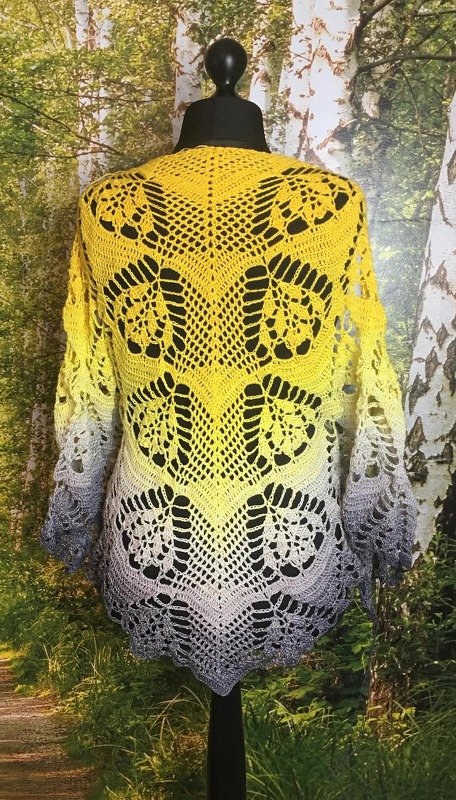 Back view of a yellow-to-gray ombre crocheted triangle shawl with lace motifs on a black mannequin.