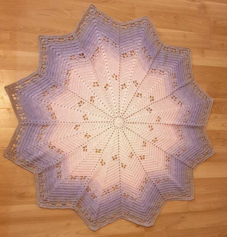 Sternförmige gehäkelte Babydecke in Creme, Rosé und Flieder auf Holzfußboden