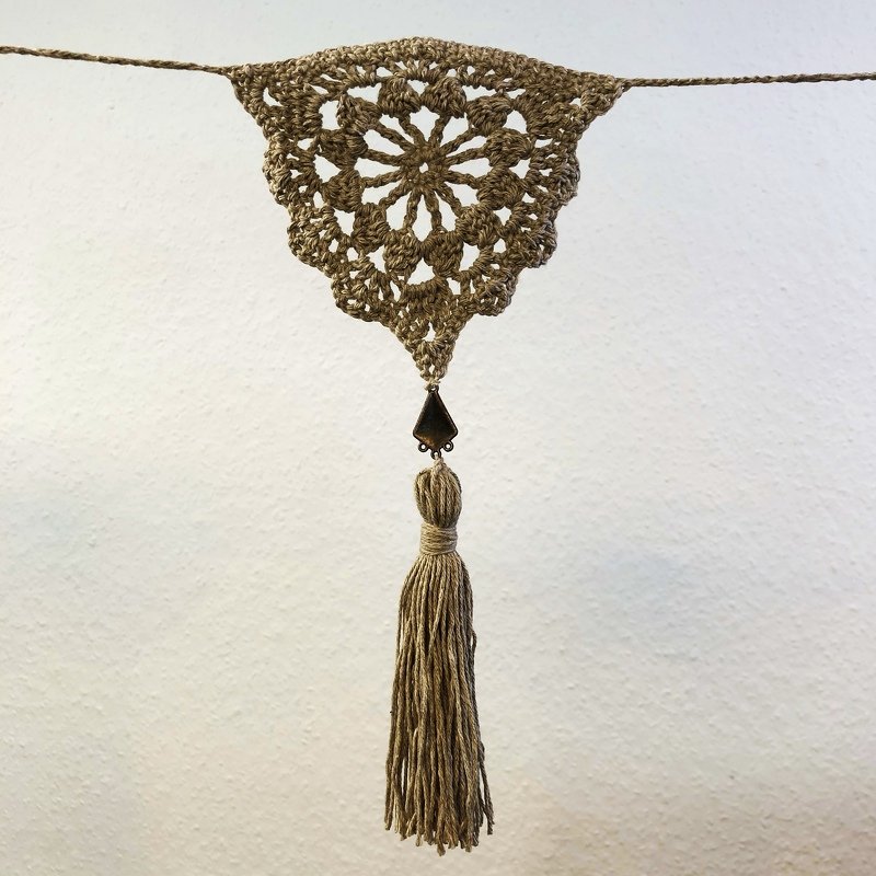 Handgehäkelter Wandbehang in Naturtönen mit Mandala-Muster und langer Quaste.