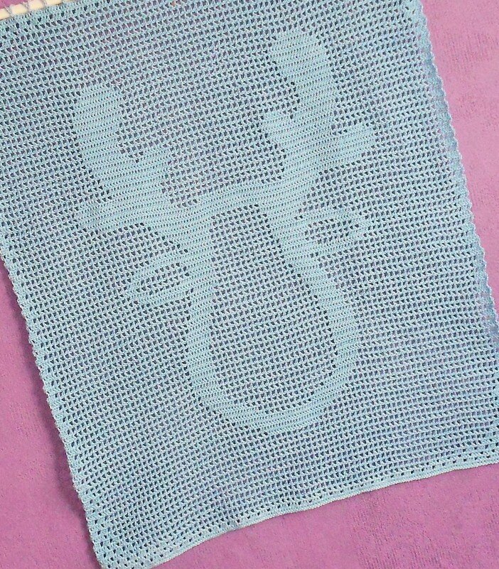 Gehäkeltes Filetquadrat mit stilisiertem Schneemann-Motiv auf lila Untergrund