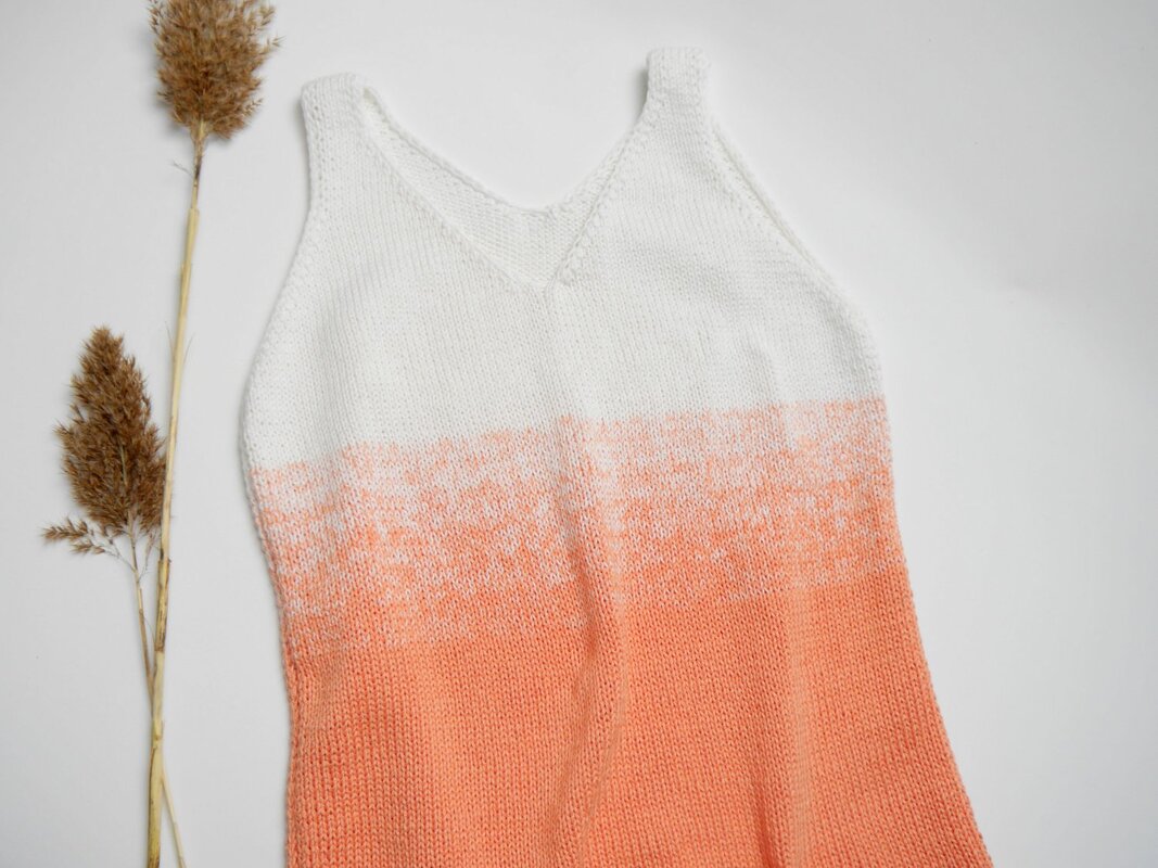 White-to-peach ombre sleeveless V-neck knit top laid flat with dried grasses