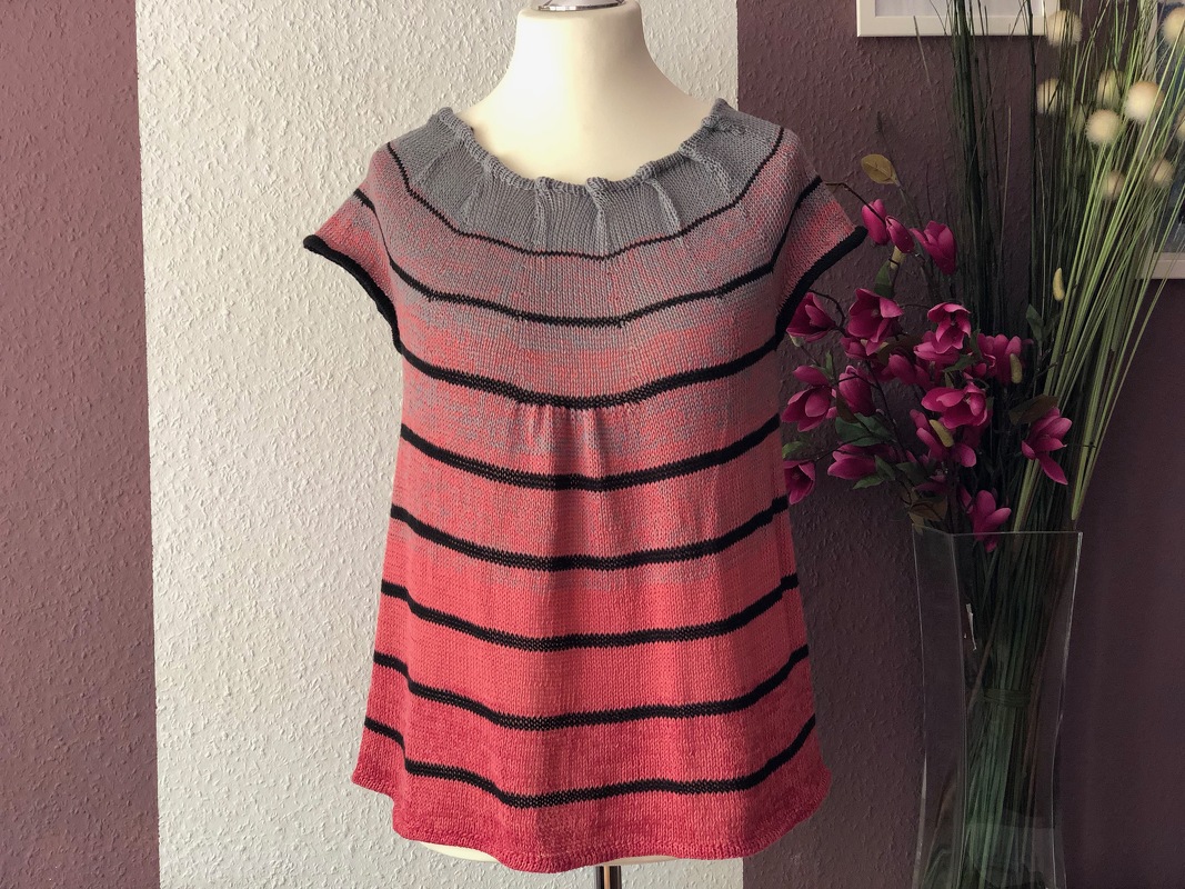 Gestricktes Damen-Top mit kurzen Ärmeln, gerüschtem Rundhalsausschnitt und horizontalen Streifen in Koralle, Grau und Schwarz auf Schaufensterpuppe.