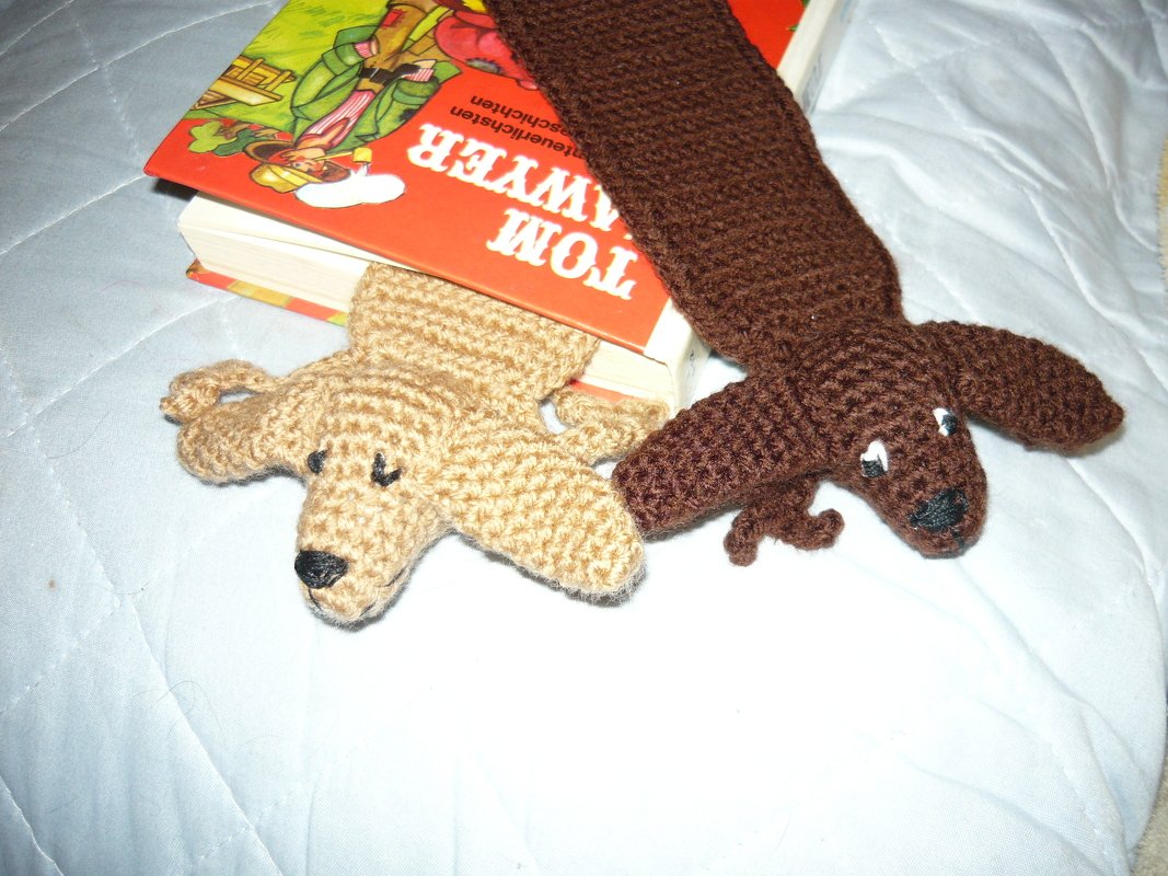 Nahaufnahme flacher gehäkelter Hund-Lesezeichen in Beige und Braun neben einem Buch