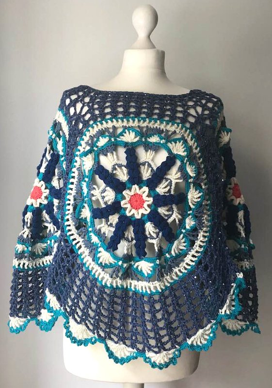 Gehäkelter Damenponcho in Blau- und Cremetönen mit großem Mandala-Motiv auf Schaufensterpuppe