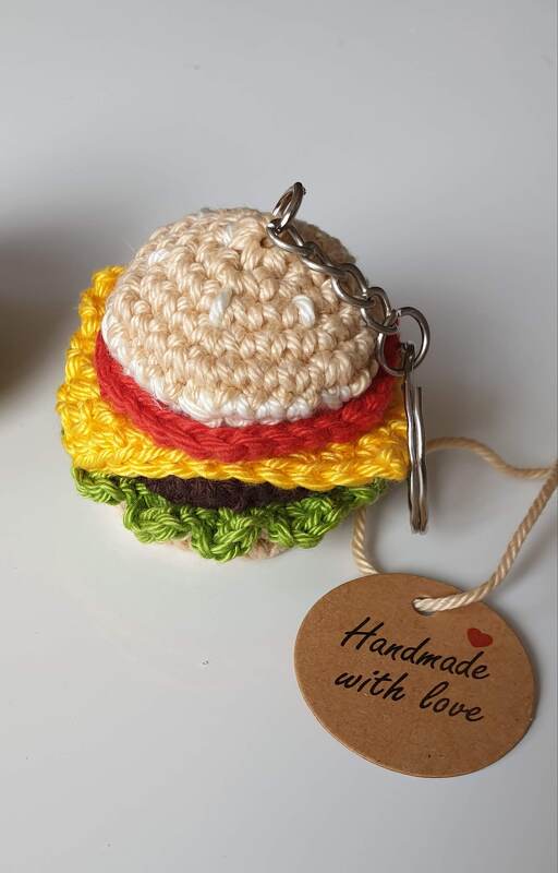 Seitliche Ansicht eines gehäkelten Hamburger‑Schlüsselanhängers mit sichtbaren Garnschichten und Metallring.