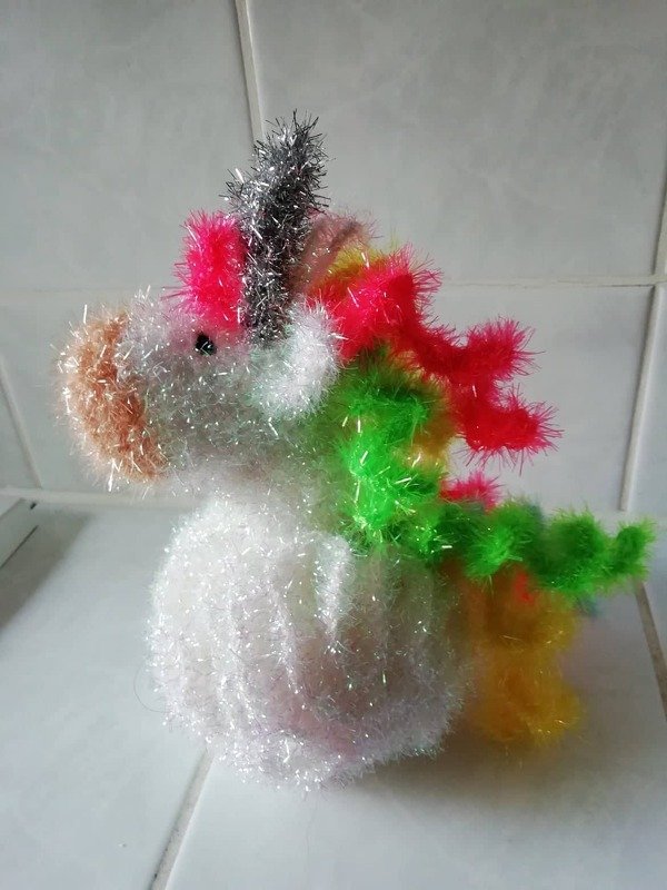Gehäkeltes flauschiges Einhorn in Weiß mit silbernem Horn und neonfarbener Mähne