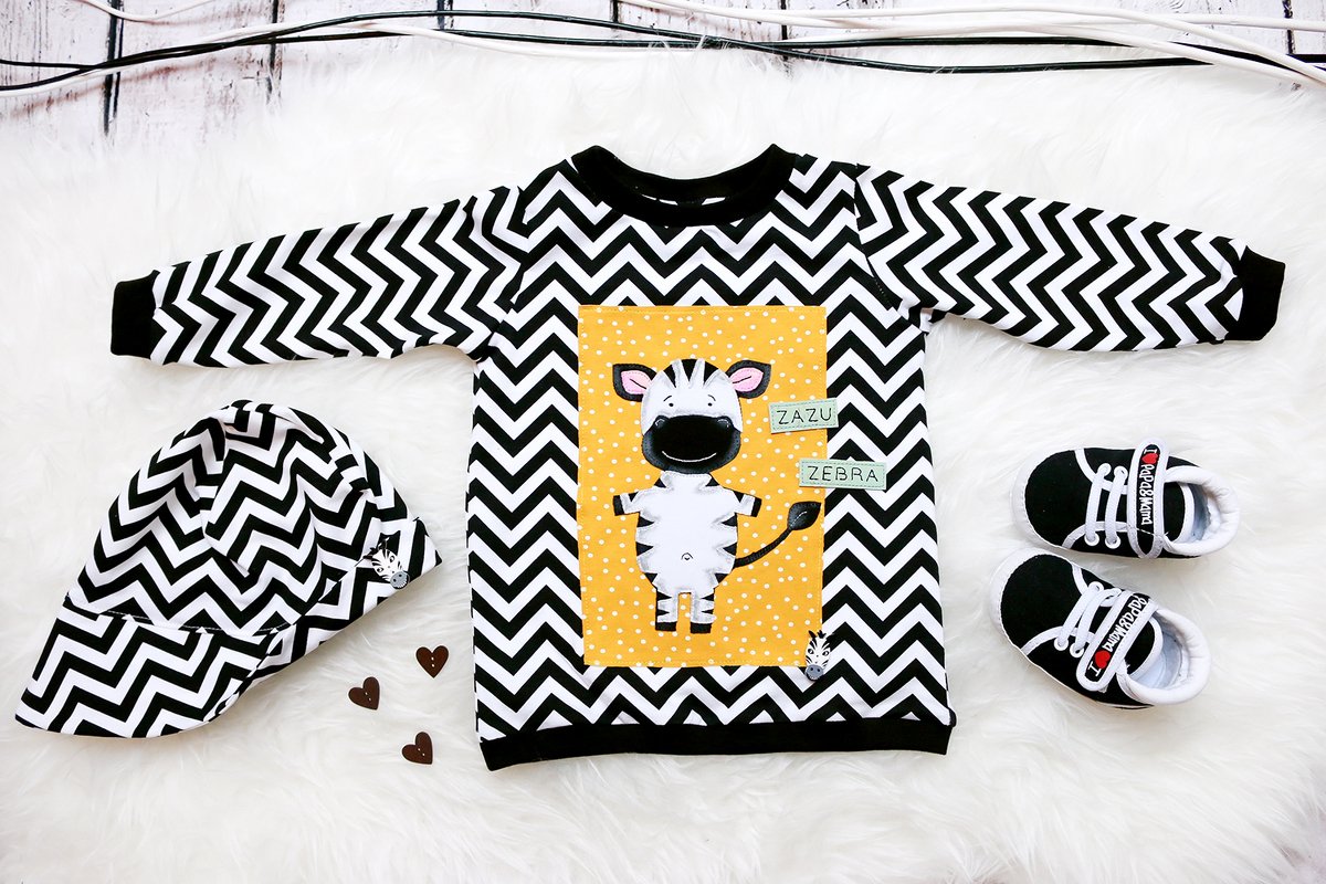 Kinder-Sweatshirt mit gelbem Panel und Zebra-Applikation, begleitet von Mütze und Babyschuhen