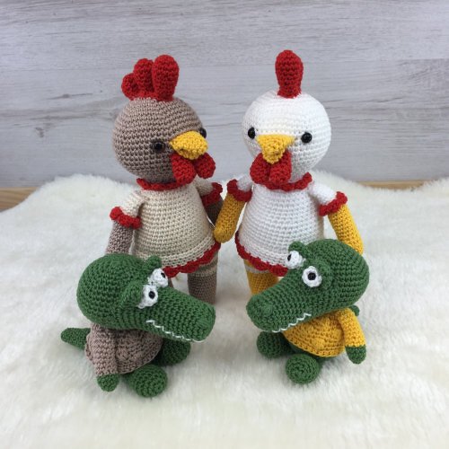 Vier Amigurumi-Häkeltiere: zwei Hühner und zwei grüne Krokodile auf hellem, weichem Untergrund
