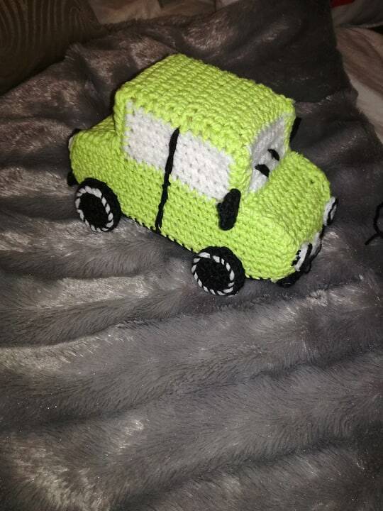 Nahaufnahme eines grünen Amigurumi-Autos mit sichtbarer Karosserie und Rädern