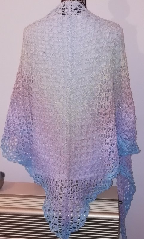 Gehäkeltes Dreieckstuch in Pastellfarben mit dezentem Schimmer, Verlauf von Weiß über Rosa und Lila bis Hellblau, offenes Netzmuster, auf einer Schneiderpuppe drapiert.