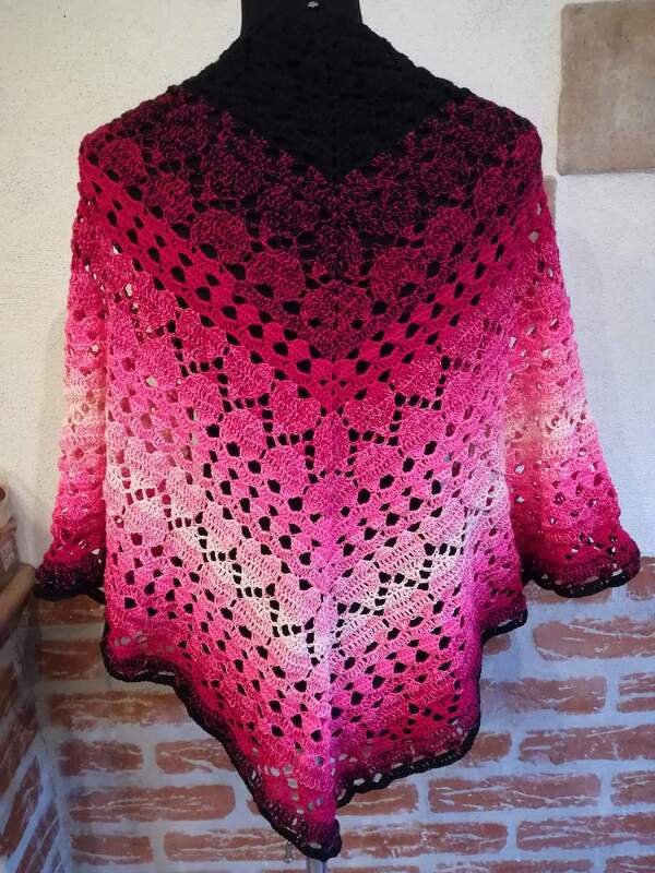 Gehäkeltes Dreieckstuch mit pinkem Ombré-Farbverlauf und Lochmuster auf einer Schneiderpuppe drapiert.