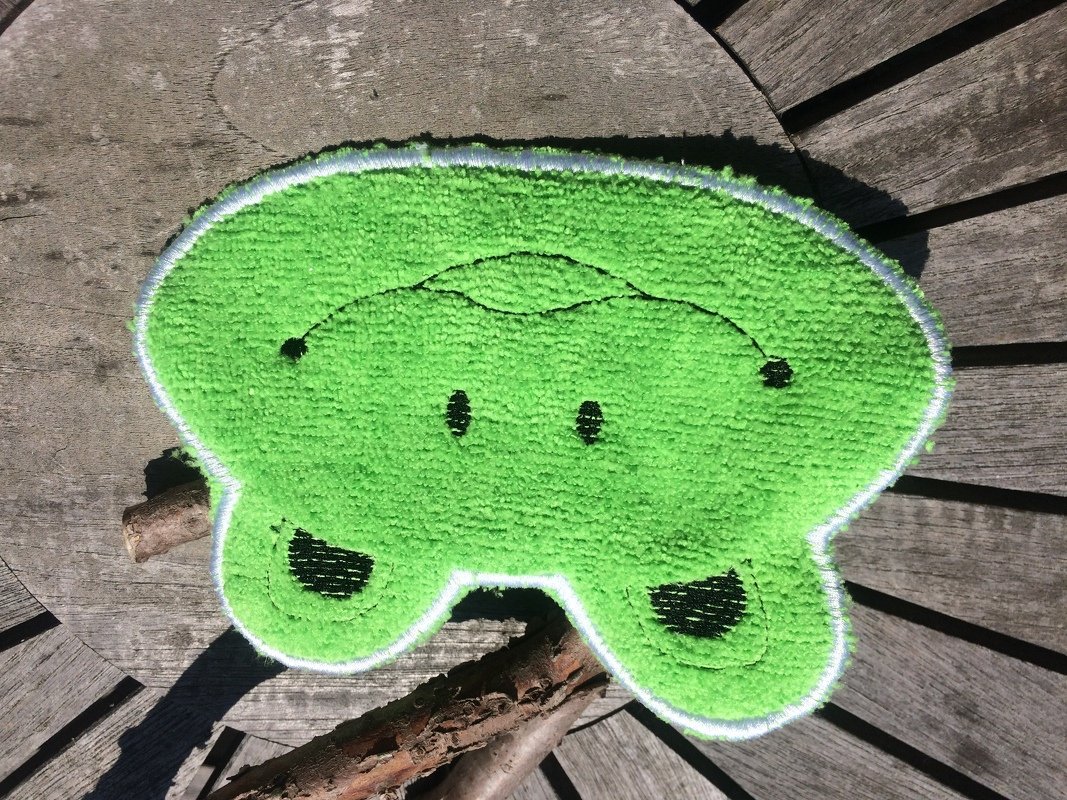 Grünes Froschgesicht aus Frottee mit weißer Satinkante und schwarzen Stickdetails