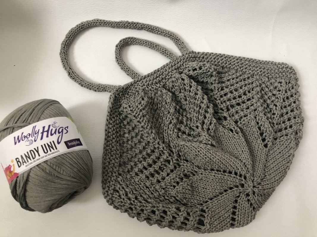 Grau gestrickte Netztasche mit Lochmuster und Garnknäuel