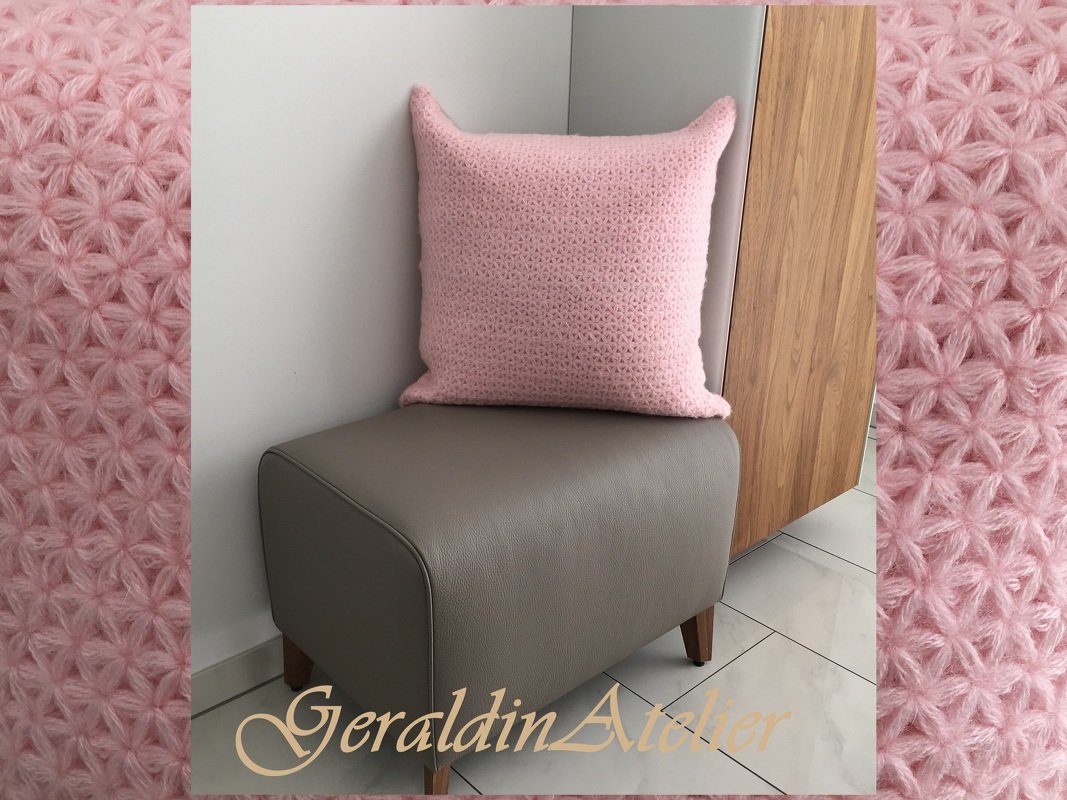 Rosa gehäkeltes Kissen mit Strukturmuster auf grauem Hocker
