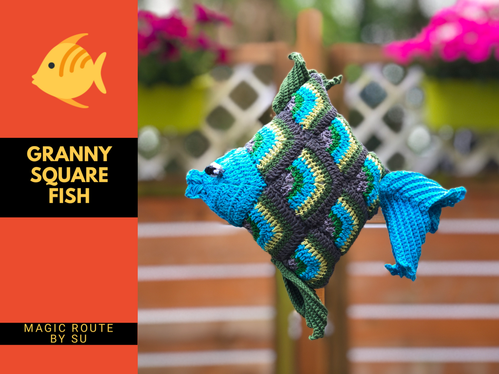 Gehäkelter Fisch aus Granny-Square-Quadraten in Blau‑, Grün‑ und Grautönen mit geformtem Schwanz und Flossen